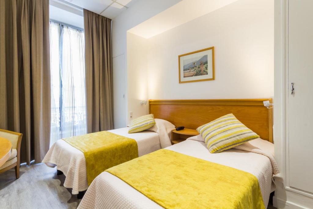 Habitación de hotel con 2 camas y ventana en Hotel Busby, en Niza