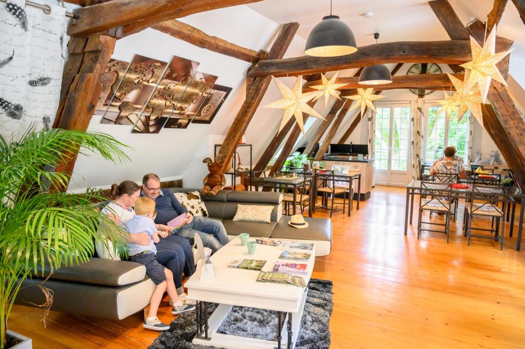 a family sitting on a couch in a living room at B&amp;B Au bois dormant chambres d hotes in Tillé