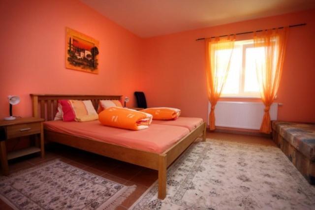 um quarto com paredes cor-de-laranja e uma cama com almofadas cor-de-laranja em Penzion Tři Koruny - budova Valerie em Havraníky