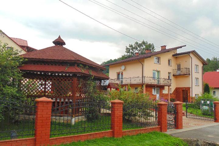 a fence with a gazebo in front of a house at Agroturystyka pod bocianim gniazdem in Górzanka