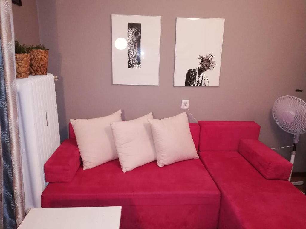 ein rotes Sofa mit weißen Kissen im Wohnzimmer in der Unterkunft Comfortable Apartment close to Spodek in Kattowitz