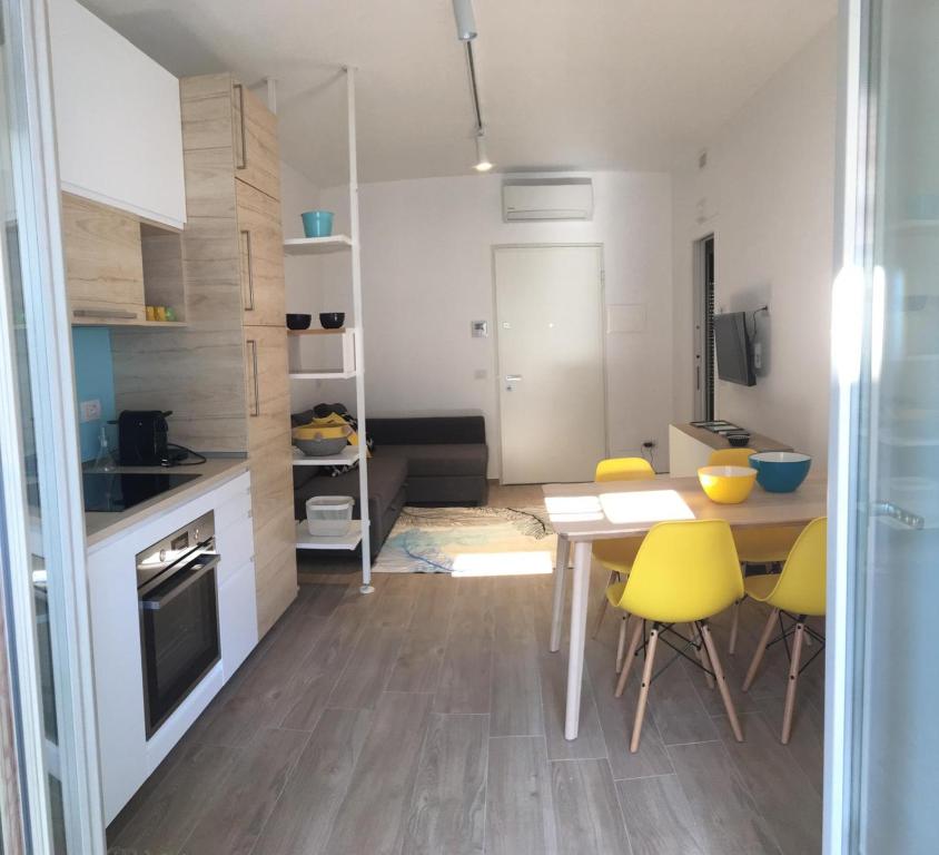kuchnia i jadalnia ze stołem i żółtymi krzesłami w obiekcie Appartamento Acquamarina w mieście San Benedetto del Tronto