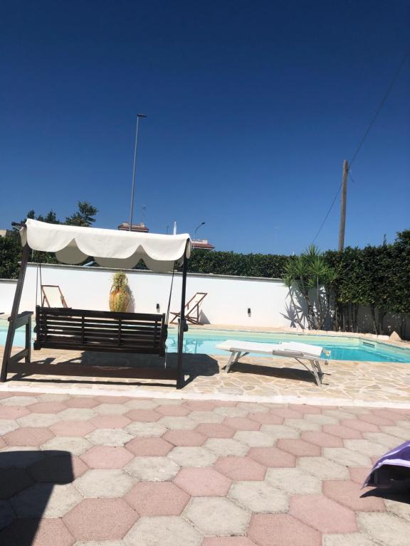 un banc avec un parasol blanc à côté de la piscine dans l'établissement Casa de Lidzia, à Cisternino