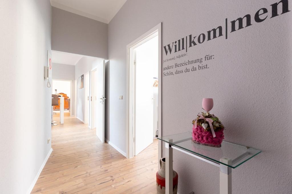 a hallway with a glass table and a wall with the words willulumulumemia at Wohnen wie zuhause - zu Gast in Erfurt in Erfurt