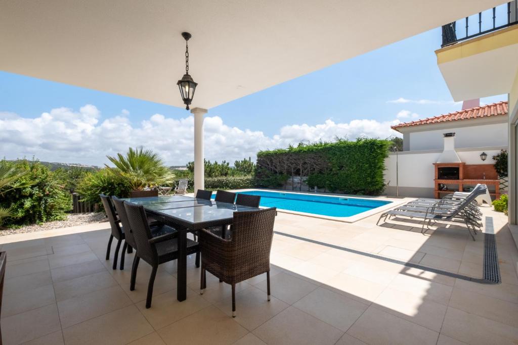 a patio with a table and chairs and a swimming pool at Magnifica Moradia V4 in Casal da Lagoa Seca