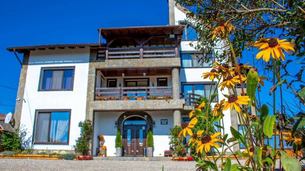 una casa blanca con flores amarillas delante en Casa Bradet, en Întorsura Buzăului