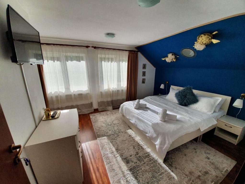 ein Schlafzimmer mit einer blauen Wand und einem Bett in der Unterkunft Casa Lucky in Râșnov