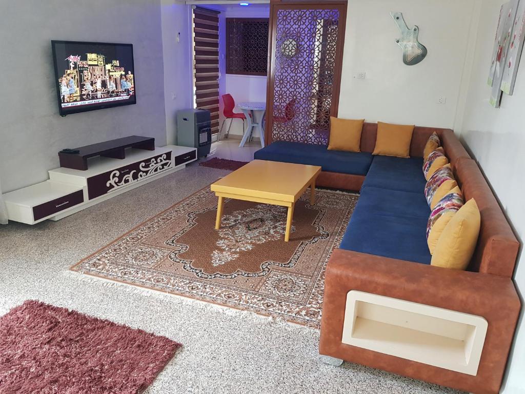 ein Wohnzimmer mit einem Sofa und einem TV in der Unterkunft APPARTEMENT "NESRINE" Kélibia in Kelibia