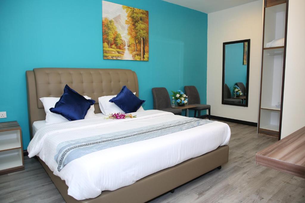 um quarto com uma cama grande e paredes azuis em S.S.HOTEL SEREMBAN em Seremban