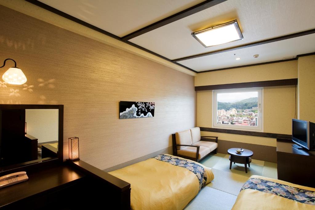 a hotel room with a bedroom with a bed and a television at Takayama Ouan in Takayama