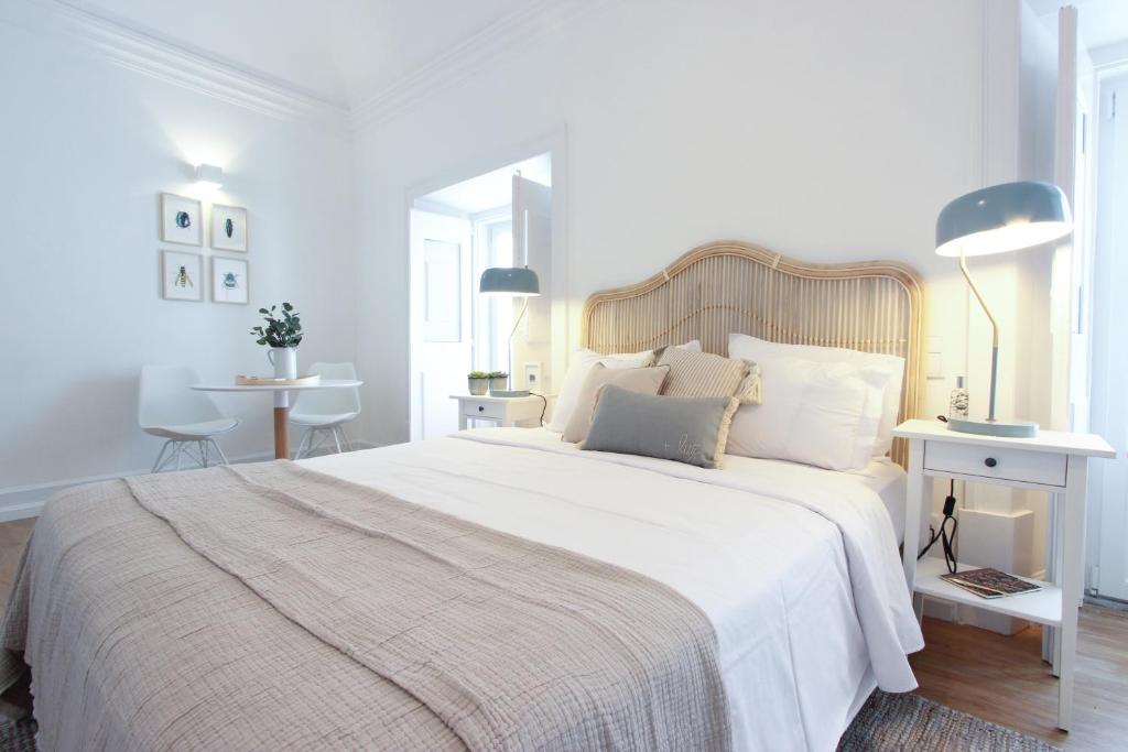 a white bedroom with a large bed with white sheets and pillows at Lavradores Boutique Guesthouse in Évora