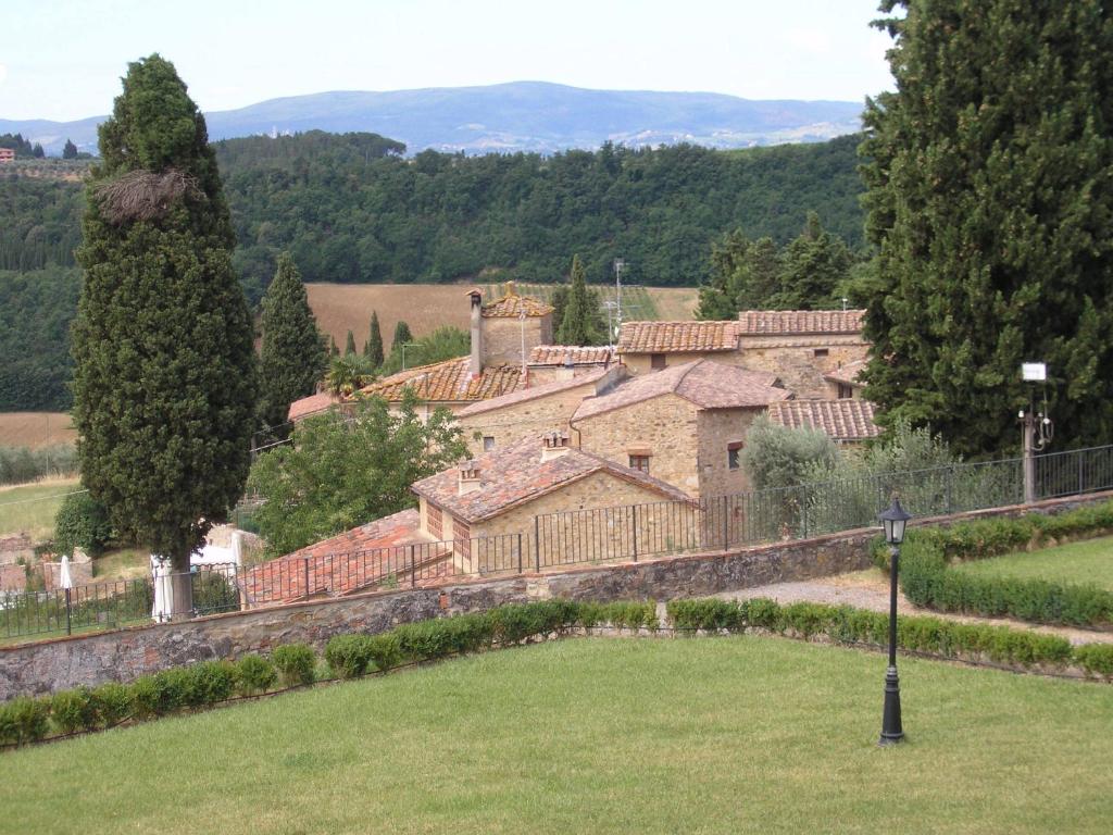 un grand bâtiment dans un champ à côté d'un arbre dans l'établissement Borghetto Di San Filippo, à Barberino di Val dʼElsa