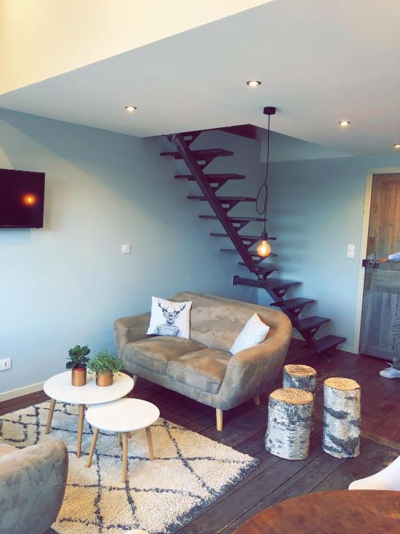 un salon avec un canapé et un escalier en colimaçon dans l'établissement Nuit en Ville Pompidou Lille La Madeleine, à La Madeleine