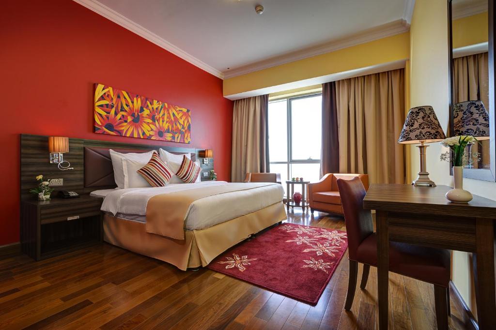 a hotel room with a large bed and a desk and a desk at Abidos Hotel Apartment Dubai Land in Dubai