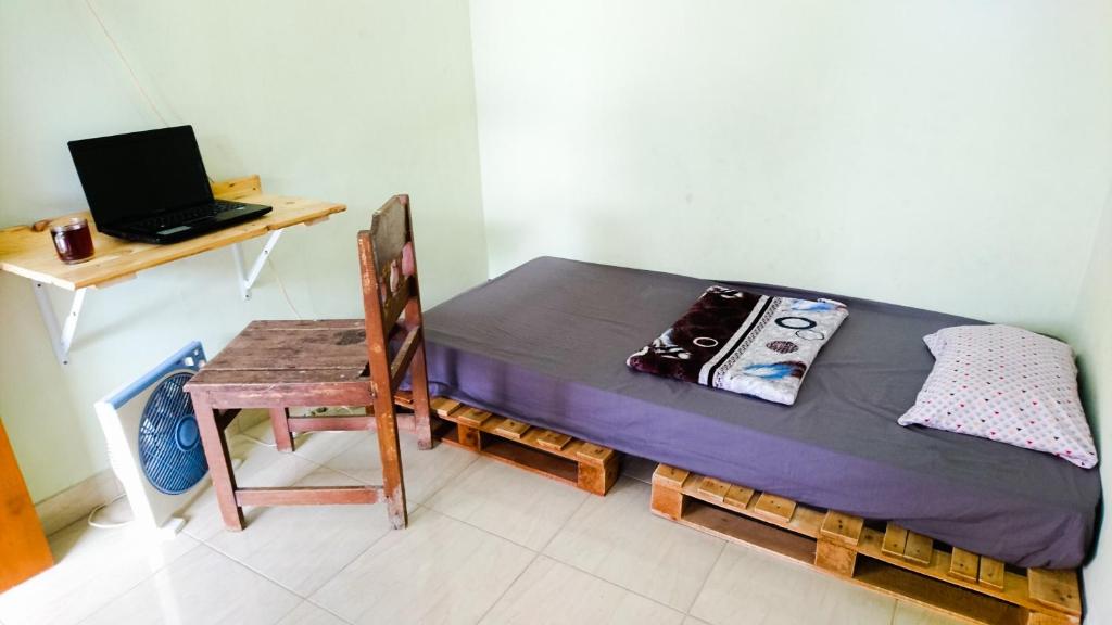 a small bedroom with a bed and a desk with a laptop at Srikaloka 12 Kostel - for Female and Couple in Yogyakarta
