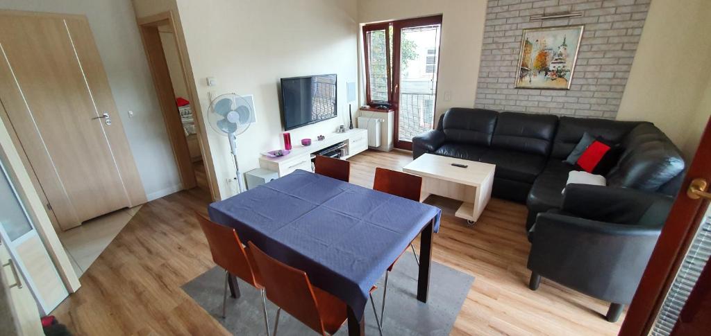 een woonkamer met een zwarte bank en een tafel bij Apartament Eve in Giżycko