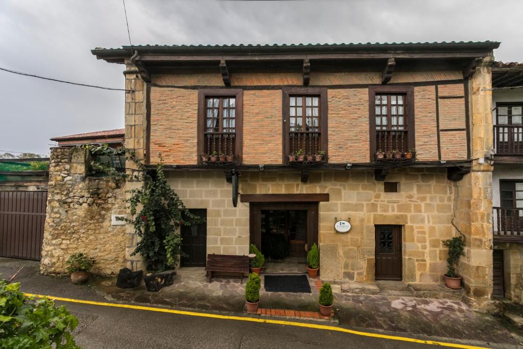 een oud bakstenen huis met een bankje ervoor bij Posada de la Abadia - Adults Only in Santillana del Mar