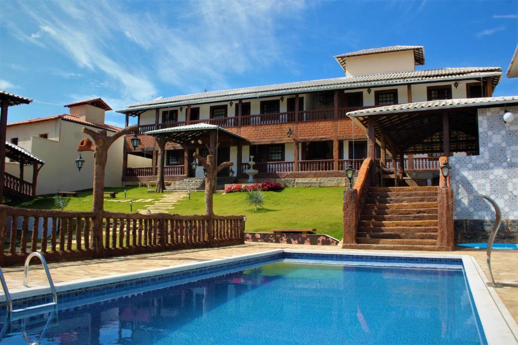 a house with a swimming pool in front of a house at Pousada Mirante Imperial in Tiradentes