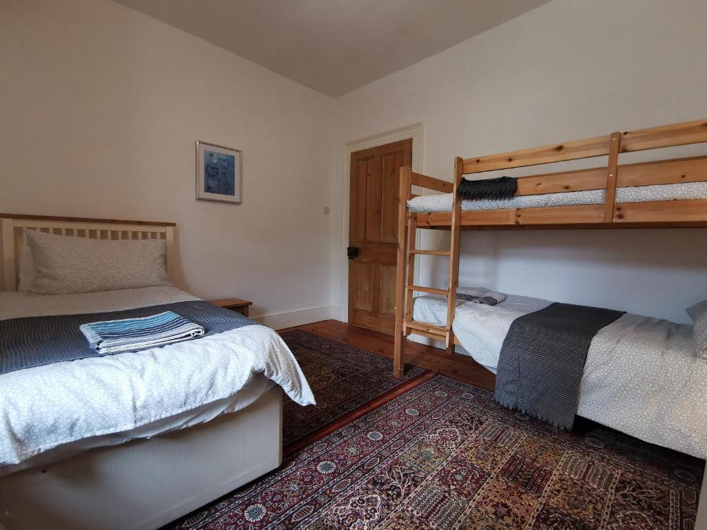 a bedroom with two bunk beds and a rug at THE OLD RECTORY KIRKULLEN LOFT APARTMENT in Jacobstow 10 mins to Widemouth bay and Crackington Haven,15 mins Bude,20 mins tintagel, 27 mins Port Issac in Jacobstow