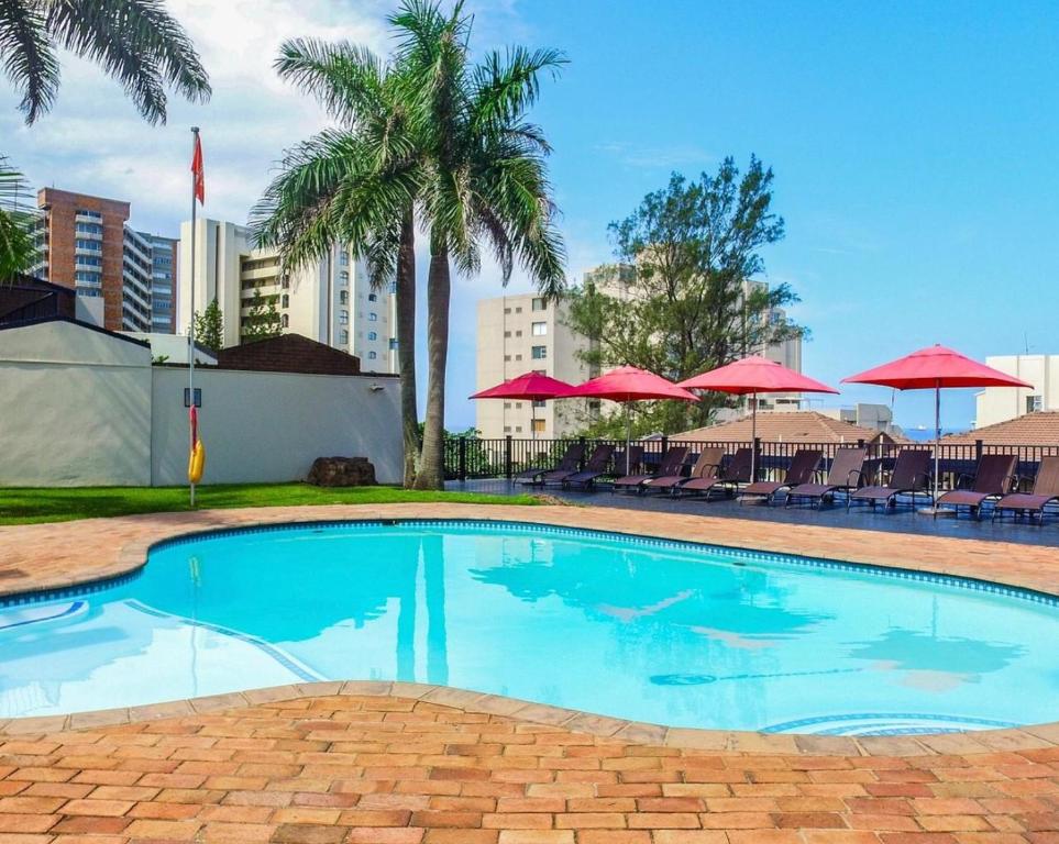 a large swimming pool with palm trees and red umbrellas at 65OnLagoonDrive 5 sleeper Self-catering Unit in Durban