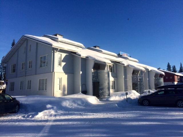 una casa coperta di neve con auto parcheggiate di fronte di Aparthotel YlläStar ad Äkäslompolo