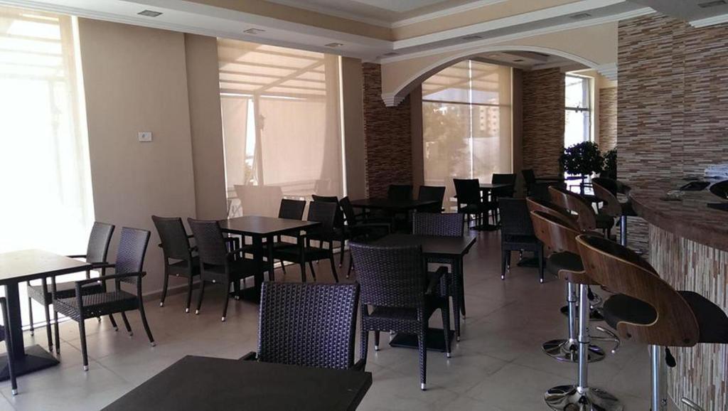 uma sala de jantar com mesas, cadeiras e janelas em Byblos Guest House em Jbeil