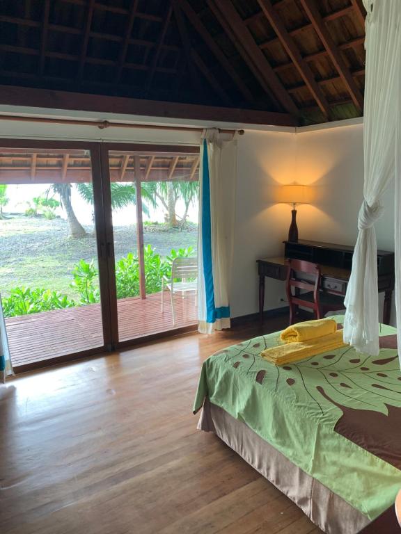 a bedroom with a bed and a desk and a window at Punatea Village in Afaahiti