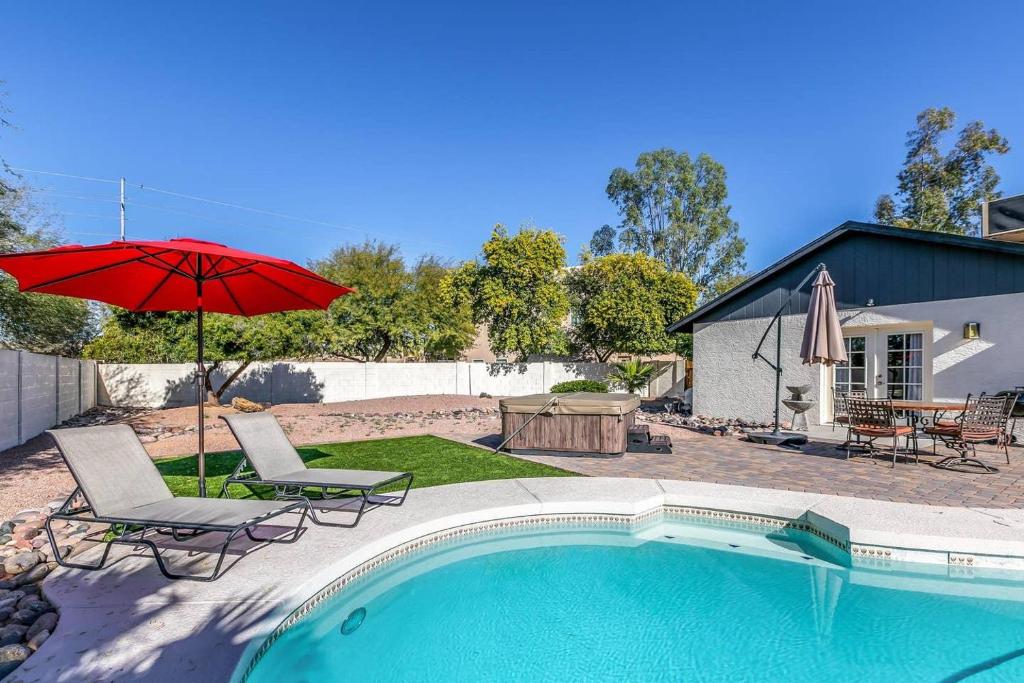 uma piscina com duas cadeiras e um guarda-sol vermelho em Bell Villa - Resort Living - Pool - Location - Events em Phoenix