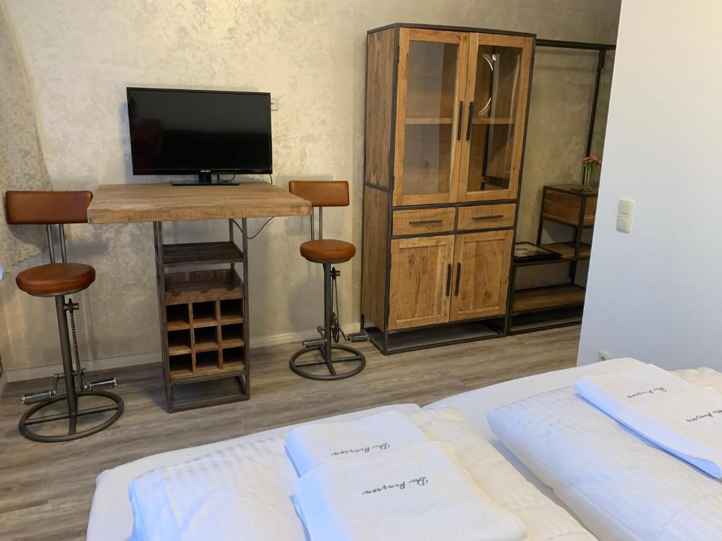 sypialnia z łóżkiem i telewizorem oraz stół ze stołkami w obiekcie Haus 8 w Lubece