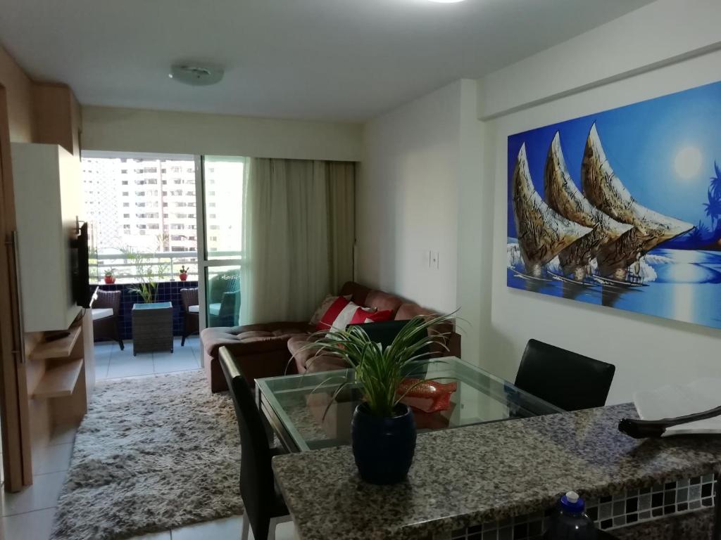 uma sala de estar com uma mesa de vidro e um sofá em Beach Class Rosalux 707 em Fortaleza