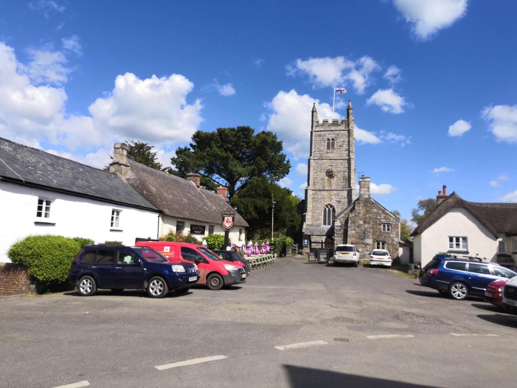 a church with a tower and cars parked in a parking lot at Church View House in Drewsteignton