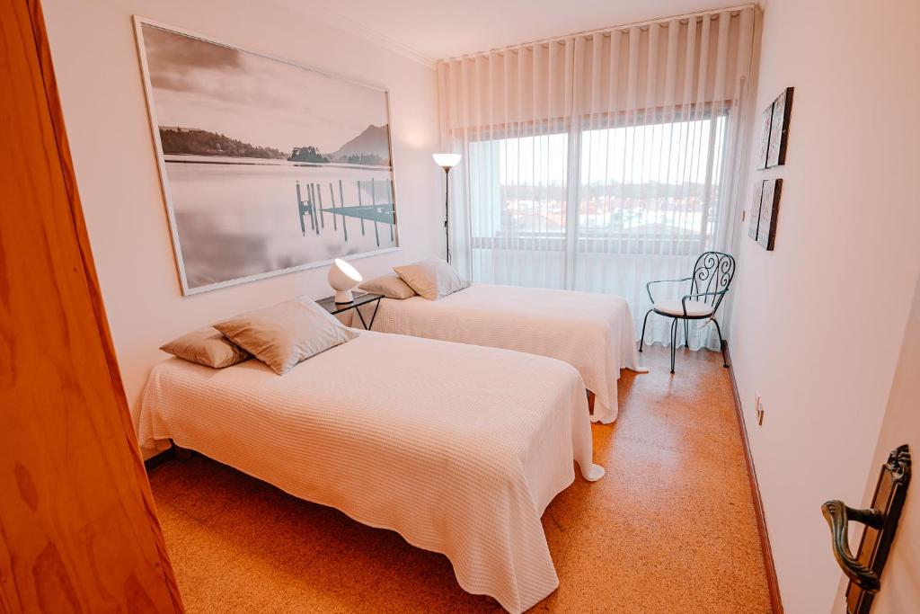a hotel room with two beds and a window at Bela Vista in Viana do Castelo