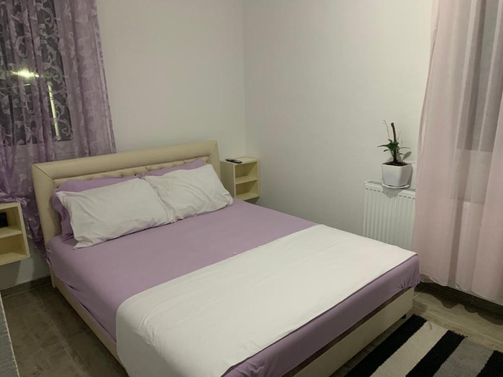 ein Schlafzimmer mit einem weißen Bett mit lila und weißen Kissen in der Unterkunft Emro-S in Novi Pazar