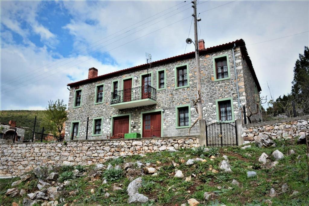 an old stone house with red doors and a stone wall at Casa di Cardellino in Psarádes