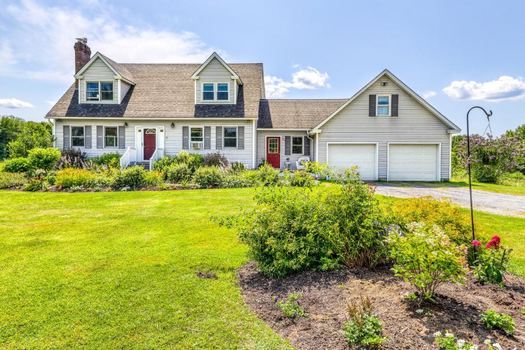 a white house with red doors and a yard at Vermont Getaway in Waterbury Center