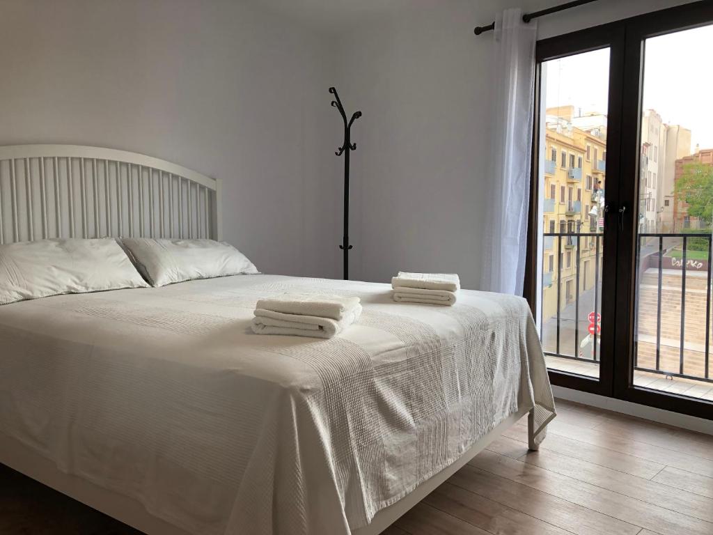 ein Schlafzimmer mit einem weißen Bett und Handtüchern darauf in der Unterkunft Descalzos Apartment - Old Town in Tarragona