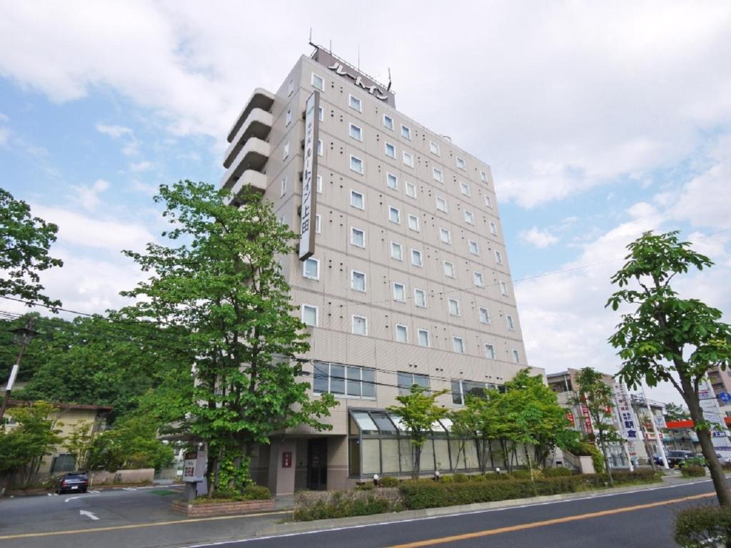 un edificio blanco alto al lado de una calle en HOTEL ROUTE-INN Ueda - Route 18 -, en Ueda