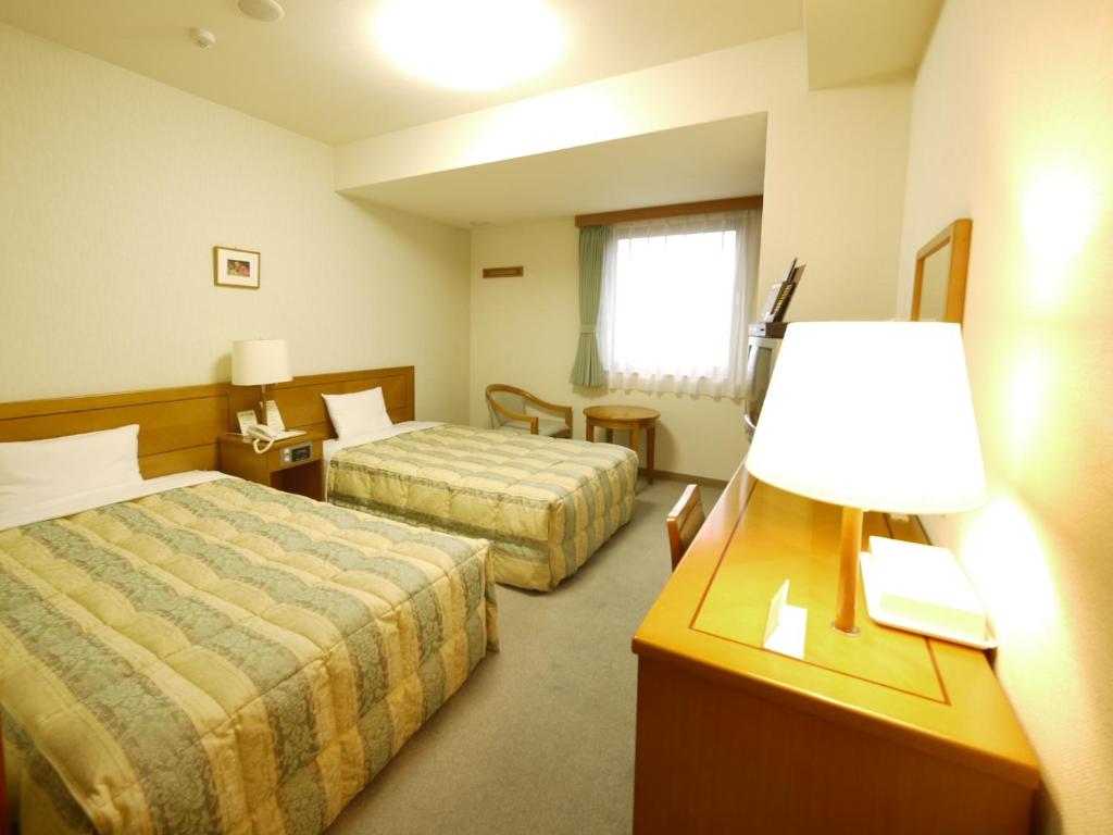 a hotel room with two beds and a lamp at Hotel Route-Inn Jouetsu in Joetsu