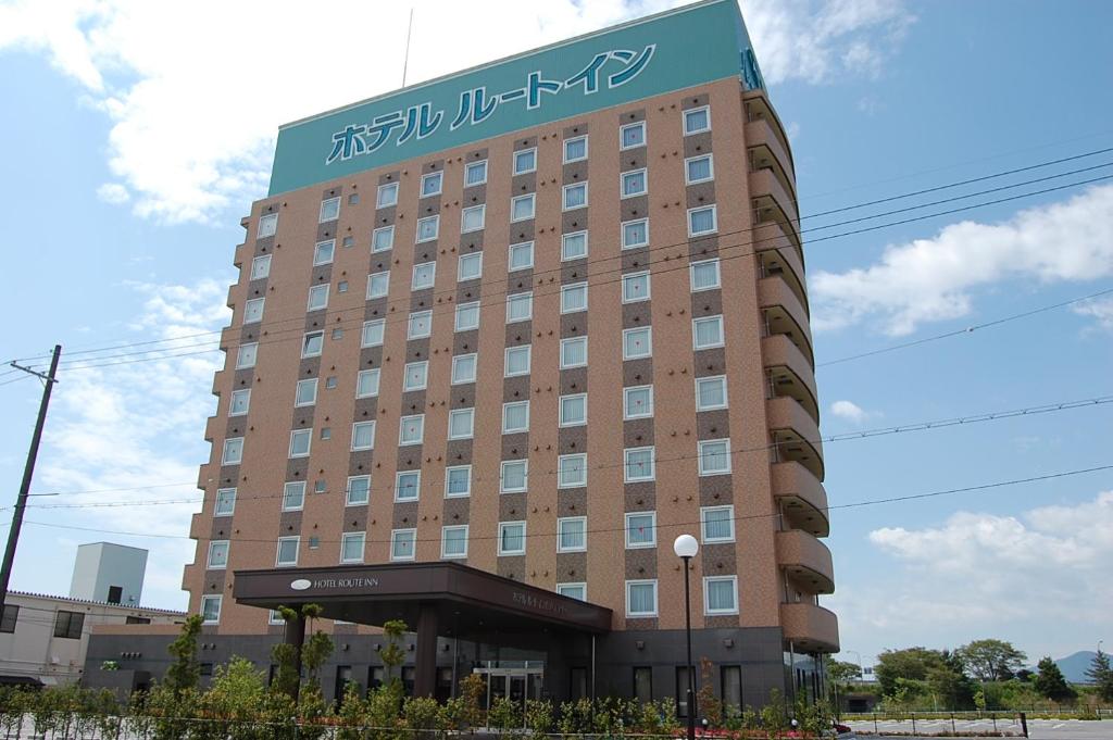 ein großes braunes Gebäude mit einem Schild drauf in der Unterkunft Hotel Route-Inn Nagahama Inter in Nagahama