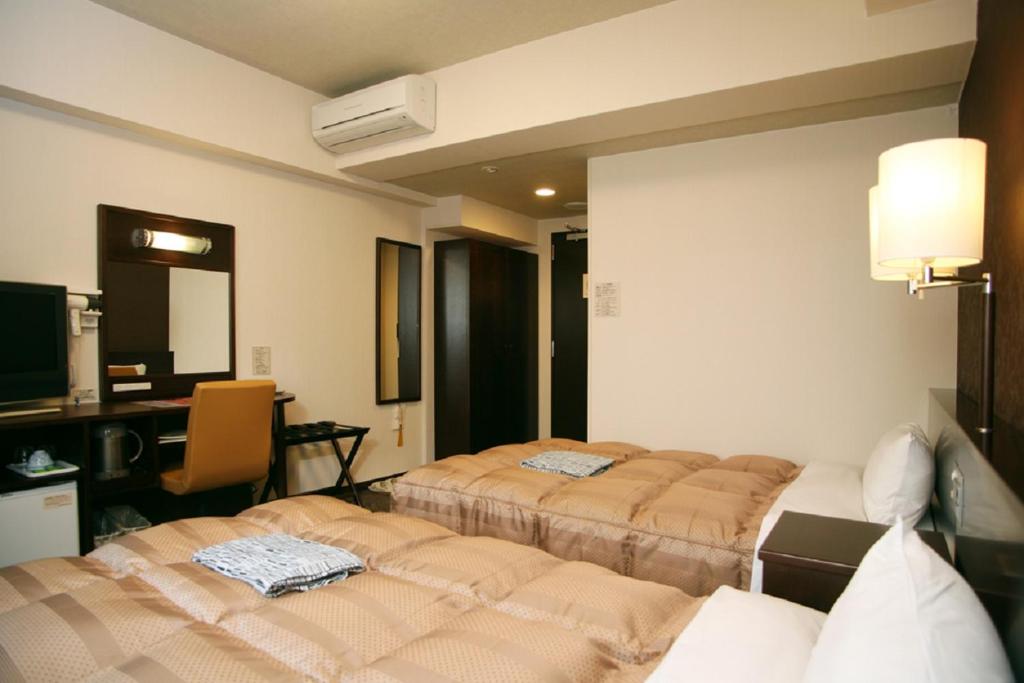 周南市にあるホテルルートイン徳山駅前のベッド2台とデスクが備わるホテルルームです。