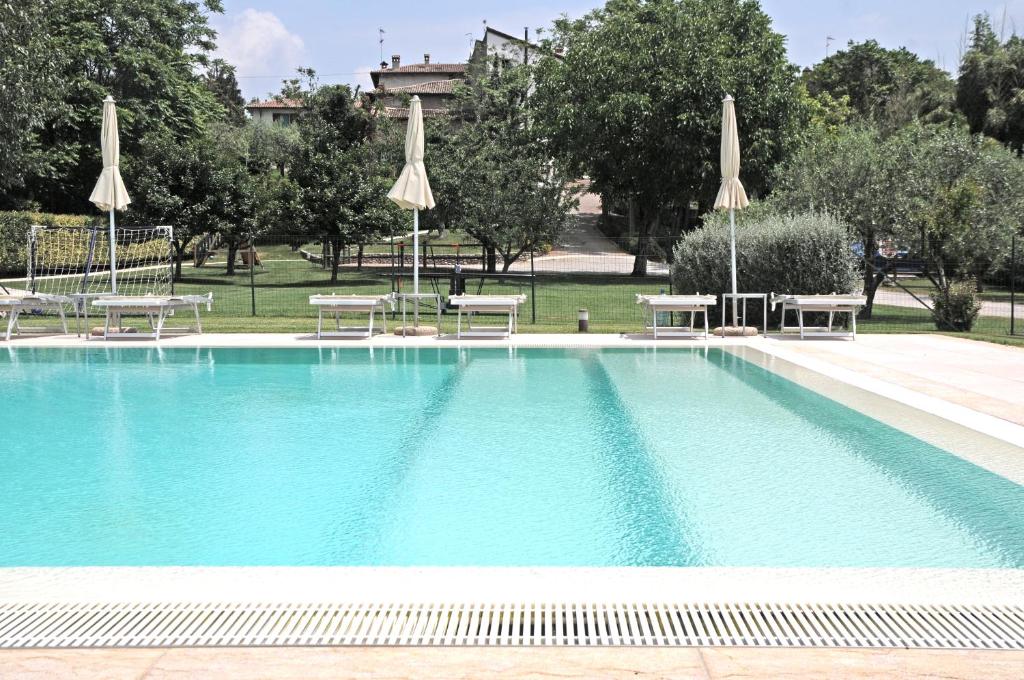 uma grande piscina com mesas e guarda-sóis em Agriturismo Borgo di Calmasino em Bardolino