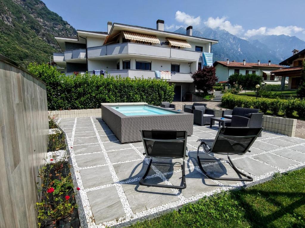 une terrasse avec 2 chaises et une piscine en face d'une maison dans l'établissement VALCHIAVENNA - B&B - Affittacamere - Guest House - Appartamenti - Case Vacanze - Home Holiday, à Chiavenna