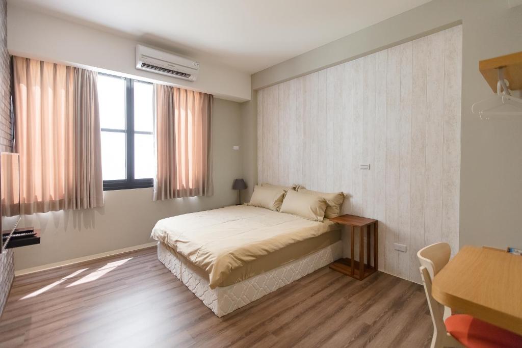 a bedroom with a bed and a table and a window at Wow Haha Foodie House in Anping
