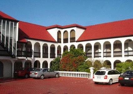 ein großes Gebäude mit Autos auf einem Parkplatz in der Unterkunft Alcala Motor Lodge in Dunedin