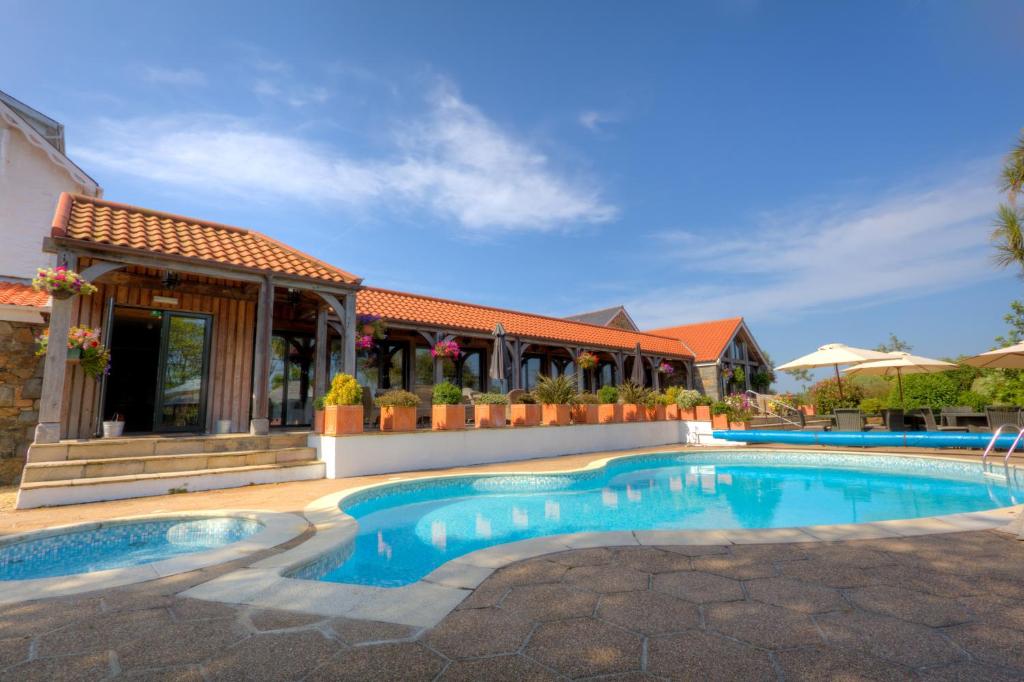 a swimming pool in front of a house at The Farmhouse Hotel and Restaurant in St Saviour Guernsey