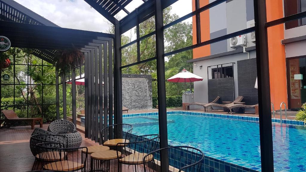 a swimming pool with tables and chairs next to a building at Baan Bangkok 97 Hotel in Pathum Thani
