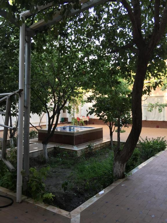 un parc avec un banc, des arbres et une fontaine dans l'établissement Munis, à Samarcande