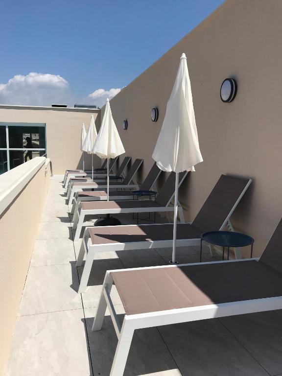 a row of tables with white umbrellas on a roof at Cristal Hôtel & Spa in Cannes