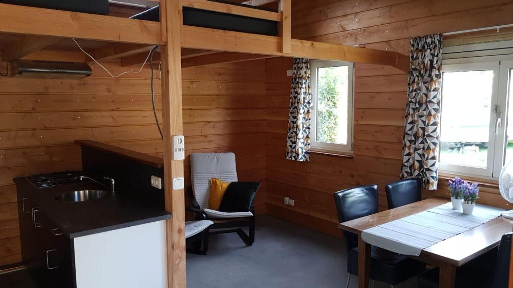 a kitchen and dining room in a log cabin at Chalet - Camping 't Dekske in Wintelre