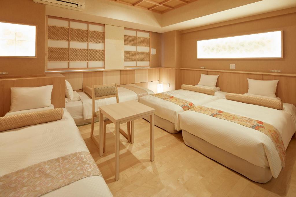 東京にあるホテルマイステイズ浅草橋のベッド3台、テーブル、椅子が備わる客室です。